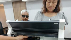 Mrs. Kwai Nan, Mitarbeiterin der HBM in Myanmar, mit dem Schulleiter U Tin Moe vor dem neuen Brailledrucker