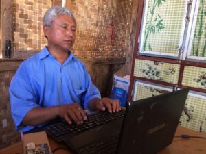U Tin Moe, Schuldirektor Bawa-Thit in Myanmar, schreibt am Laptop
