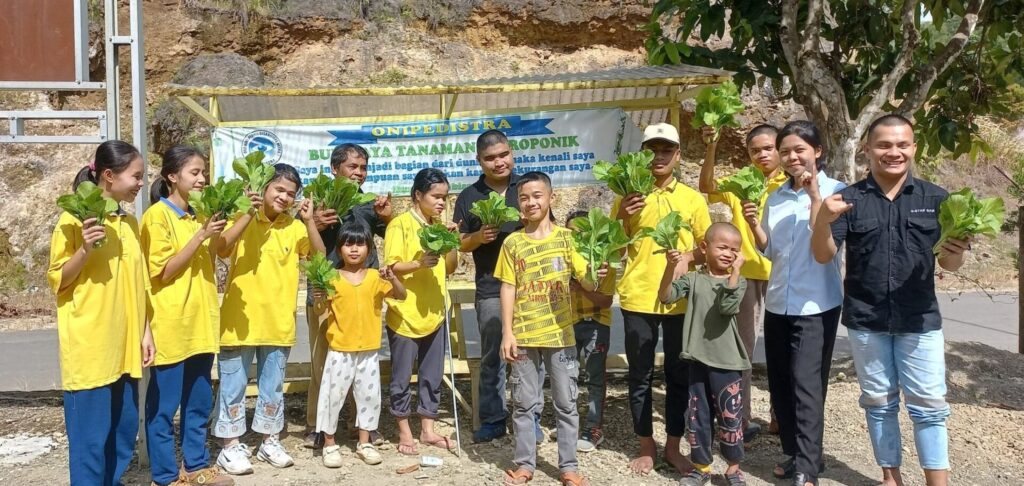 Gruppenfoto aus Oni Pedistra, Kinder winken mit Pflanzen