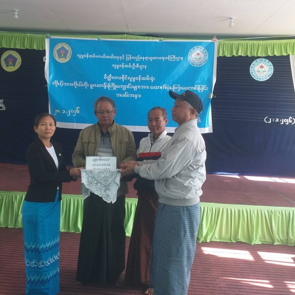 Gruppenfoto vor einem Plakat zur Eröffnung der Sporthalle der New Life (Bawathit) Blind School in Myanma