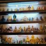 Großer Glasschrank mit 4 Regalböden voll mit unterschiedlichen Buddhas. Alle sind schlank. Die meisten im Schneidersitz, einige nur als Büste, aber mit unterschiedlicher Hand- und Fingerstellung und aus unterschiedlichem Material... Gold, Messing, Alabaster und anderen Steinen. Das Foto ist aufgenommen in einer kleineren Pagode in Yangon, Myanmar.