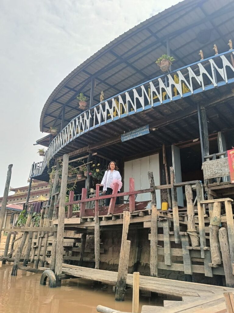 Kwai Nan aus Myanmar steht auf dem Balkon eines Hauses auf Pfählen, darunter Wasser